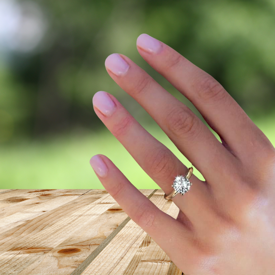Hand wearing an IGI certified 2ct D color diamond VVS1 VVS2 3EX solitaire ring on wooden surface